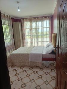 a bedroom with a bed in a room with windows at Kio Farm Retreat 2 in Kiserian