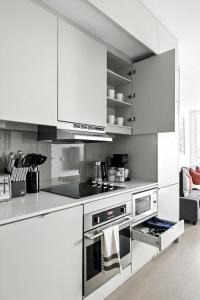 een witte keuken met witte kasten en apparaten bij Chic Downtown Retreat with Private Patio in Toronto