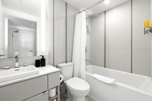 een witte badkamer met een toilet en een wastafel bij Chic Downtown Retreat with Private Patio in Toronto