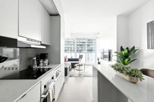 een keuken met witte apparatuur en een woonkamer bij Chic Downtown Retreat with Private Patio in Toronto +24 foto's