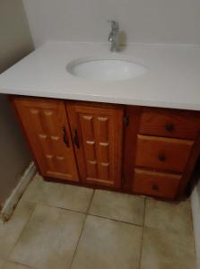 a bathroom with a white sink and wooden cabinets at Central Location New Year Stay- Free Parking & Fast Wifi in Kitchener