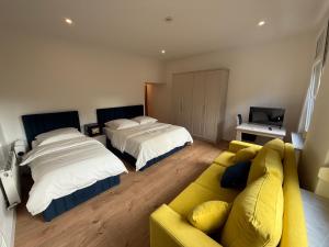 ein Wohnzimmer mit 2 Betten und einem gelben Sofa in der Unterkunft Hotel &Restaurant Meteora in Glauchau