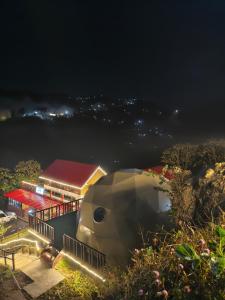 a large building with a red roof at night at The Kamcha Geodesic dome & Homestay in Bomdila