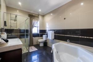 a bathroom with a tub and a sink and a toilet at Amara Mountain View George in George +17 photos