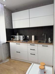een keuken met witte kasten en een spoelbak bij Квартира in Karagandy