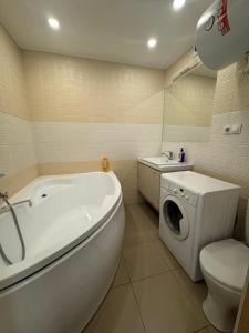 een badkamer met een bad en een wasmachine bij Квартира in Karagandy