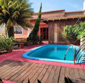 a pool with a wooden deck next to a house at Sossego Ponta da Fruta in Vila Velha