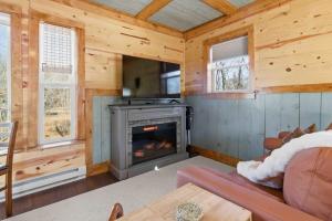 a living room with a fireplace in a log cabin at NEW! BEAR Necessities tiny home, outdoor theater! in Garrison