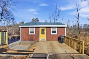 a tiny house with a wooden ramp and a yellow door at NEW! BEAR Necessities tiny home, outdoor theater! in Garrison