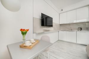 Premium Studio in OVO في فروتسواف: مطبخ أبيض مع طاولة و إناء من الزهور