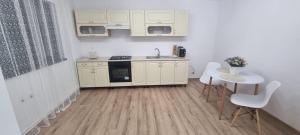 a kitchen with white cabinets and a table and chairs at Casa CDC in Şimnicu de Sus
