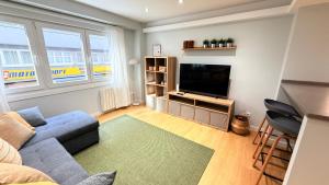 a living room with a blue couch and a flat screen tv at Fogar de Breogan in A Coruña