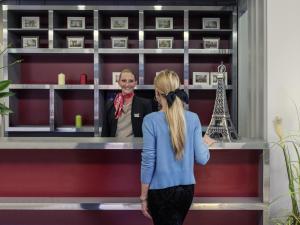 a woman standing at a counter with a man at Mercure Cergy Pontoise Centre in Cergy