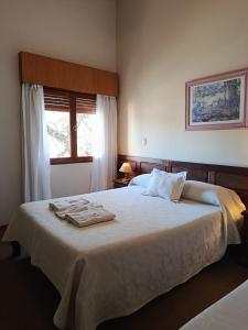 San Pedro Hotel في ريو سيبالوس: غرفة نوم بها سرير كبير مع مناشف عليه