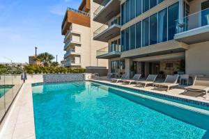 een zwembad met stoelen en een gebouw bij Ocean Vista Aruba in Palm-Eagle Beach