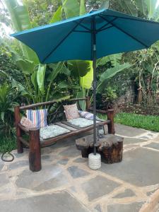 Kwa Nzeu في شاطئ دياني: مقعد مع مظلة زرقاء على الفناء
