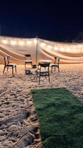 a group of picnic tables in the sand at night at Skyrak in Umm al Qurayn +2 photos