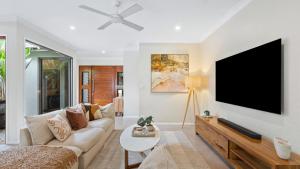 een woonkamer met een bank en een flatscreen-tv bij Shambala at Palm Cove in Palm Beach