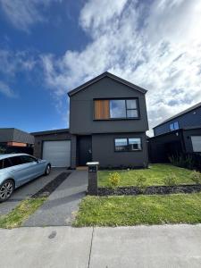 a black house with a car parked in a driveway at New 4BR Family Home in Greenhill Park, Chartwell in Hamilton