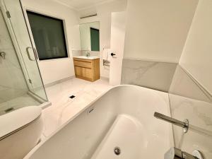 a bathroom with a tub and a toilet and a sink at New 4BR Family Home in Greenhill Park, Chartwell in Hamilton