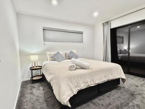 a white bedroom with a large bed with a window at New 4BR Family Home in Greenhill Park, Chartwell in Hamilton