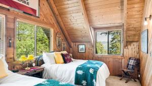 2 Betten in einem Zimmer mit Holzwänden und Fenstern in der Unterkunft Big Tree Lodge Cozy Cabin w Firepit Piano Bar Deck in Fawnskin