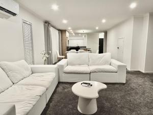 a living room with two white couches and a table at New 4BR Family Home in Greenhill Park, Chartwell in Hamilton