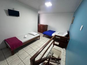 a small room with two beds and a tv at CANAS Praia Hotel Lounge in Florianópolis