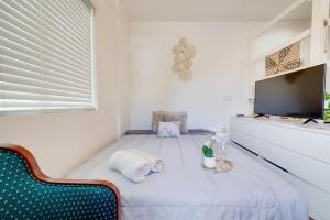 a white room with a bed and a flat screen tv at Work and Play! Studio Retreat 2 Mi to Dtwn Riverside in Riverside