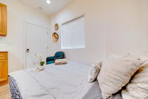 a white bedroom with a bed and a blue chair at Work and Play! Studio Retreat 2 Mi to Dtwn Riverside in Riverside