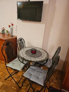 a table with chairs and a television on a wall at Happy apartment-OldTown Sarajevo in Sarajevo