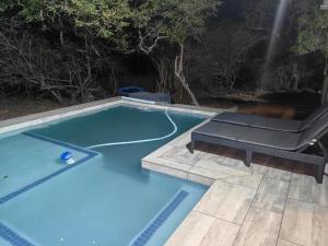 a blue swimming pool with a table and a bench at Eagle's Retreat in Marloth Park