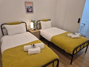 two beds with towels on them in a room at Stokey Six in London