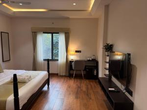 Hotel Aventus - by Urbantara في إندوري: غرفة نوم بها سرير ومكتب وتلفزيون