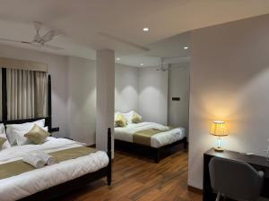 Hotel Aventus - by Urbantara في إندوري: سريرين في غرفة في الفندق مع مكتب ومكتب