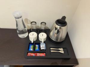 Hotel Aventus - by Urbantara في إندوري: صينية سوداء عليها آلة صنع القهوة والمشروبات موضوعة على طاولة