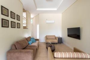een woonkamer met een bank en een tv bij Refúgio de Luxo à beira do Lago Passaúna, in Ferraria