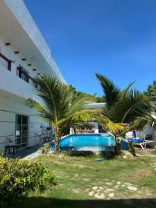 a swimming pool with two palm trees next to a building at VILLA GRANDEZZA in Punta Cana