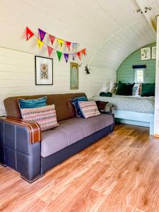 a living room with a couch and a bed at The Mainstay Pod at Hidden Wood Glamping in Corsley