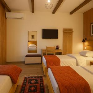 a hotel room with three beds and a flat screen tv at Guesthouse Lord Byron in Tepelenë