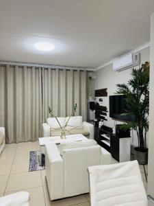 a living room with white furniture and a flat screen tv at Graceful Getaway Air B&B in Rundu