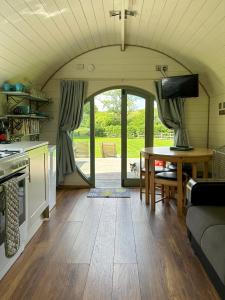 a living room with a table and a kitchen at The Mainstay Pod at Hidden Wood Glamping in Corsley