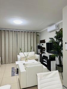 a living room with white furniture and a flat screen tv at Graceful Getaway Air B&B in Rundu +17 photos