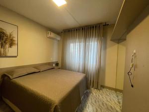 a small bedroom with a bed and a window at Apartamento na praia in Capão da Canoa