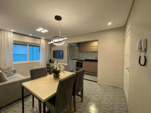 a dining room and living room with a table and chairs at Apartamento na praia in Capão da Canoa