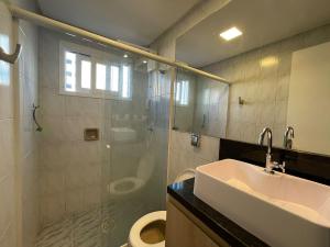 a bathroom with a sink and a shower and a toilet at Apartamento na praia in Capão da Canoa