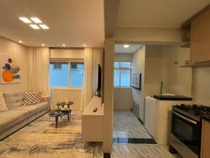 a living room with a couch and a kitchen at Apartamento na praia in Capão da Canoa +6 photos