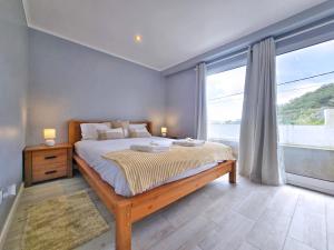 een slaapkamer met een bed en een groot raam bij Casa da Maré Azul in São Roque