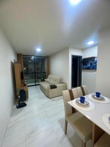 uma sala de estar com uma mesa, cadeiras e um sofá em Excelente apartamento a passos da praia em Cabedelo