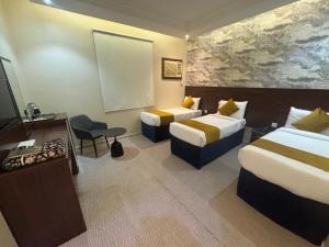 a hotel room with two beds and a television at فندق ملتقى الايمان للضيافة السياحي in Al ‘Azīzīyah